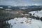 Winter landscape with small rural houses in remote settlement between snow covered forest in cold mountains