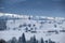 Winter landscape with small rural houses in remote settlement between snow covered forest in cold mountains