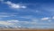 Winter landscape with a smooth hills covered with a yellow dry grass and snow under dark blue sky with spectacular clouds