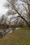 Winter landscape without snow around the river Jihlava. Trees without leaves. Standing water of the river