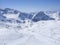 Winter landscape with snow covered mountain slopes and pistes with skiers enjoying spring sunny day at ski resort Stubai