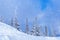 Winter landscape with snow falling, trees in snow and blue sky. Sheregesh ski resort in Russia, Siberia