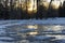 Winter landscape with sunrise over a snow field with frozen puddles