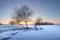 Winter landscape at sunset. Snowy nature Icy lake covered by snow and sun on horizon. Christmas time