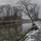 Winter landscape of Ukrina river, snowy banks and naked trees in riparian zone