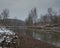 Winter landscape of Ukrina river, snowy banks and naked trees in riparian zone