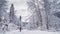 Winter landscape - view of the snowy road with a walking hiker in the winter forest