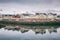 Winter landscape with white and red houses, reflection in the water and snowy mountain peaks, Kabelvag, Lofoten Islands, Norway