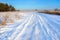 Winter landscape. Winter country road in the background of the forest. Traces of cars