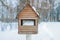 Winter landscape. Wooden birdhouse in snow-covered garden. Blurry photography with a shallow depth of field. Cold winter day