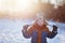 Winter little child playing throws up snow outdoors during snowfall. Active outoors leisure with children in winter on cold snowy