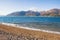 Winter Mediterranean landscape on calm sunny day. Sea, snow-crowned mountains and deserted pebble beach. Montenegro, Bay of Kotor