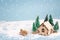 Winter miniature house with fir trees and aircraft on blue background. Copy space for text. Holiday and celebration concept.