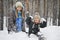 Winter mother with her son indulge sitting on the snow in the woods.