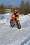 Winter motocross rider riding a wheelie through the snow