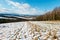 Winter mountain landscape with field, grove and village in far