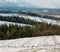 Winter mountain landscape with field, grove and village in far