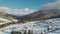 Winter mountain landscape. Houses covered with snow on a hill, forest and clouds.