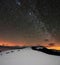 Winter mountains under starry cloudy sky