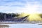 Winter natural landscape. Bare trees and twigs against blue sky on sunset. Wasteland, snow-covered river with dry reeds surrounded