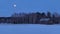 Winter night with a full moon, a house in a field blanketed in snow