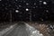 Winter night landscape with road in a field in the snow. The snowfall, blizzard and the dark sky