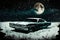 Winter night scene featuring abandoned vehicle buried in snow and large full moon in the background