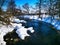 Winter northern landscape river bank in the snow in a snowy forest silence, cozy houses in the distance