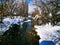 Winter northern landscape river bank in the snow in a snowy forest silence, cozy houses in the distance