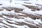 Winter old shabby wobbly wicker fence made of wooden boards. Snow blizzard