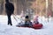 Winter outdoor recreation with a family. A man pulls two inflatable sleds with his wife and daughter sitting in them