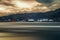 Winter panorama with windmills, the sun through the moody clouds, and motion blur on lake