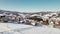 Winter panoramic view of the mountains. Flying over a field next to a village in the hills.