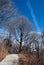 Winter park view with a trail, trees and an inversion trace in t