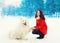 Winter and people concept - happy smiling young woman owner having fun with white Samoyed dog