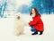 Winter and people - happy smiling young woman owner having fun with white Samoyed dog outdoors