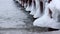 Winter pier on the shore of an unfrozen lake with ice and waves