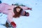 winter portrait of happy child girl playing outdoor in snowy garden, making snow angel.