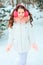 Winter portrait of happy kid girl in pink earmuffs walking outdoor in snowy winter forest