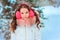 Winter portrait of happy kid girl in pink earmuffs walking outdoor in snowy winter forest