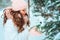 Winter portrait of happy kid girl in white coat and hat and pink mittens playing outdoor in snowy winter forest