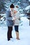 winter portrait of happy romantic couple warm up each other on the walk in snowy forest