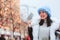 Winter portrait of happy young woman walking in Christmas city streets, decorated with garlands, toys and trees