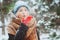 Winter portrait of happy young woman walking in snowy forest in warm outfit