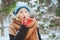 winter portrait of happy young woman walking in snowy forest in warm outfit, blowing snow under snowfall.