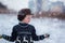 Winter portrait of little kid boy wearing a knitted sweater with deers, outdoors during snowfall.