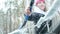 Winter portrait of a young woman clearing snow from a car windshield. Slow motion