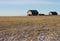 Winter prairie harvested field with abandoned barns on horizon