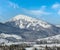 Winter remote alpine village outskirts, countryside hills, groves and farmlands view from mountain slope