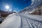 Winter road with a bridge over a mountain river. Beautiful sunny winter day with sunshine. France, Savoie, Bessans